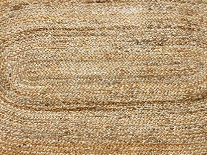 Close-up of a jute rug: beige woven pattern with fine, parallel lines and a spiral zone.