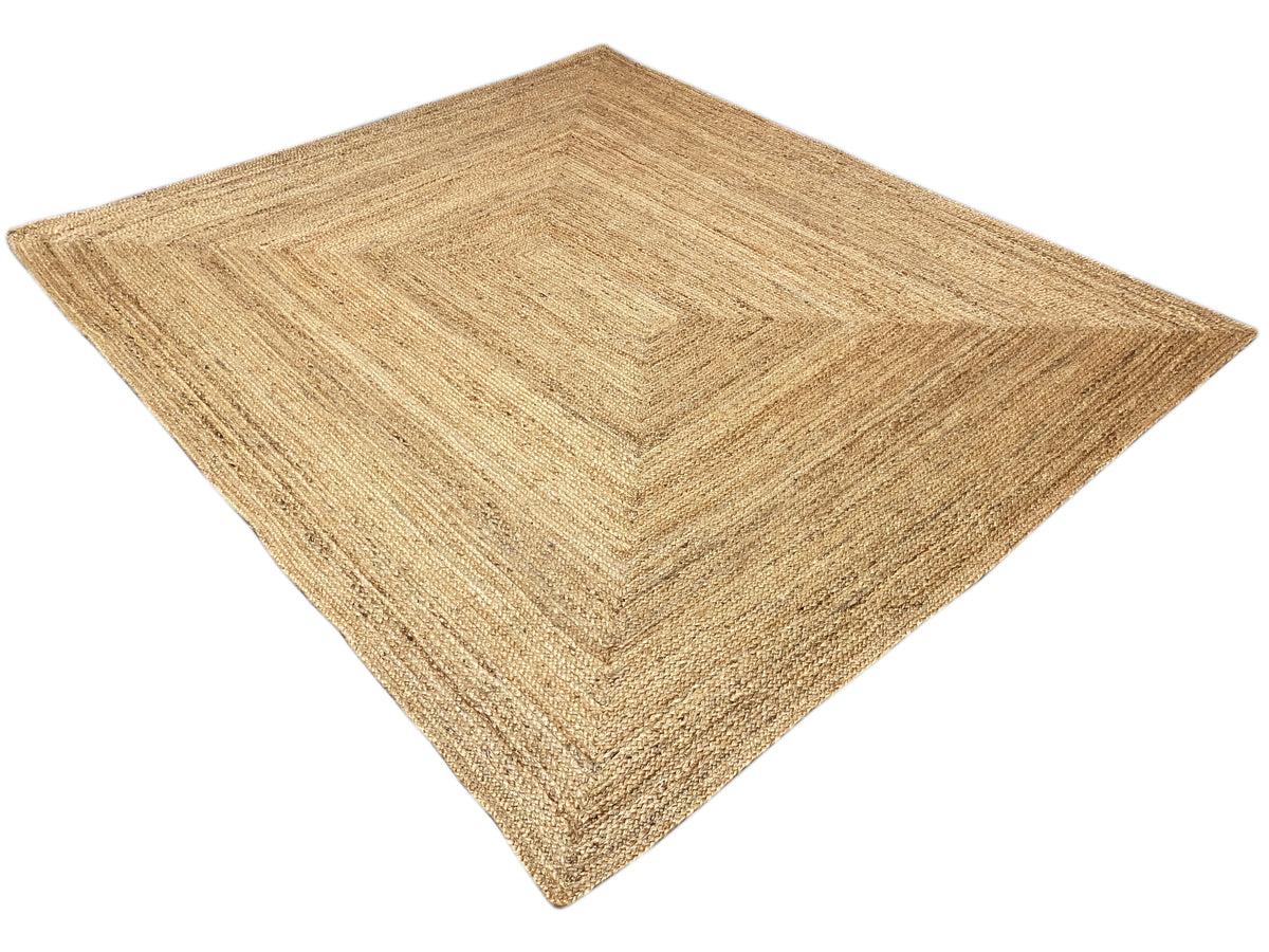 Geometric-patterned jute rug, natural beige, flat-laying, diagonal view.