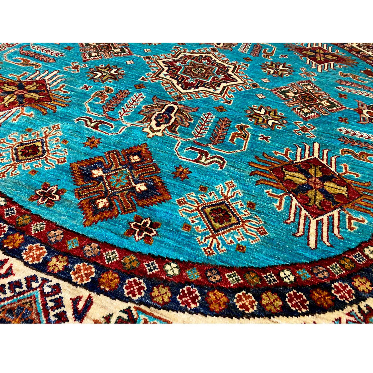 Close-up of a round rug: turquoise surface with multicolored animal and ornamental motifs