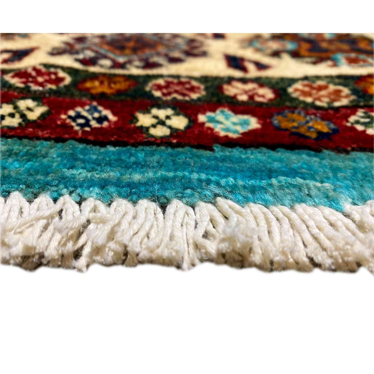 Close-up of carpet edge: turquoise pile with a white fringed trim