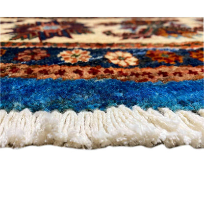 Rug edge with white fringe trim and a blue, multicolored woven pattern along the border