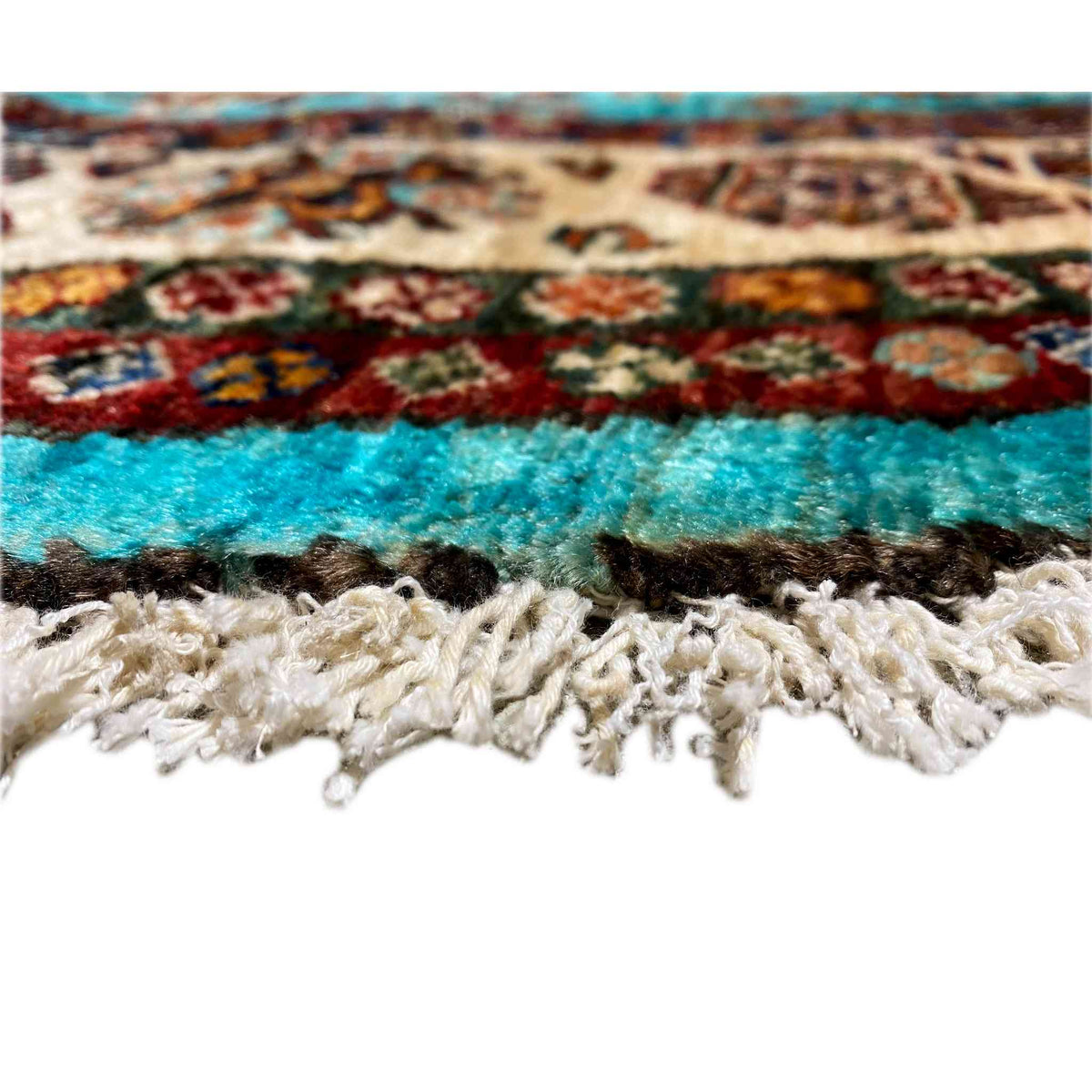 Edge detail: turquoise rug with a braided fringe finish in beige and brown