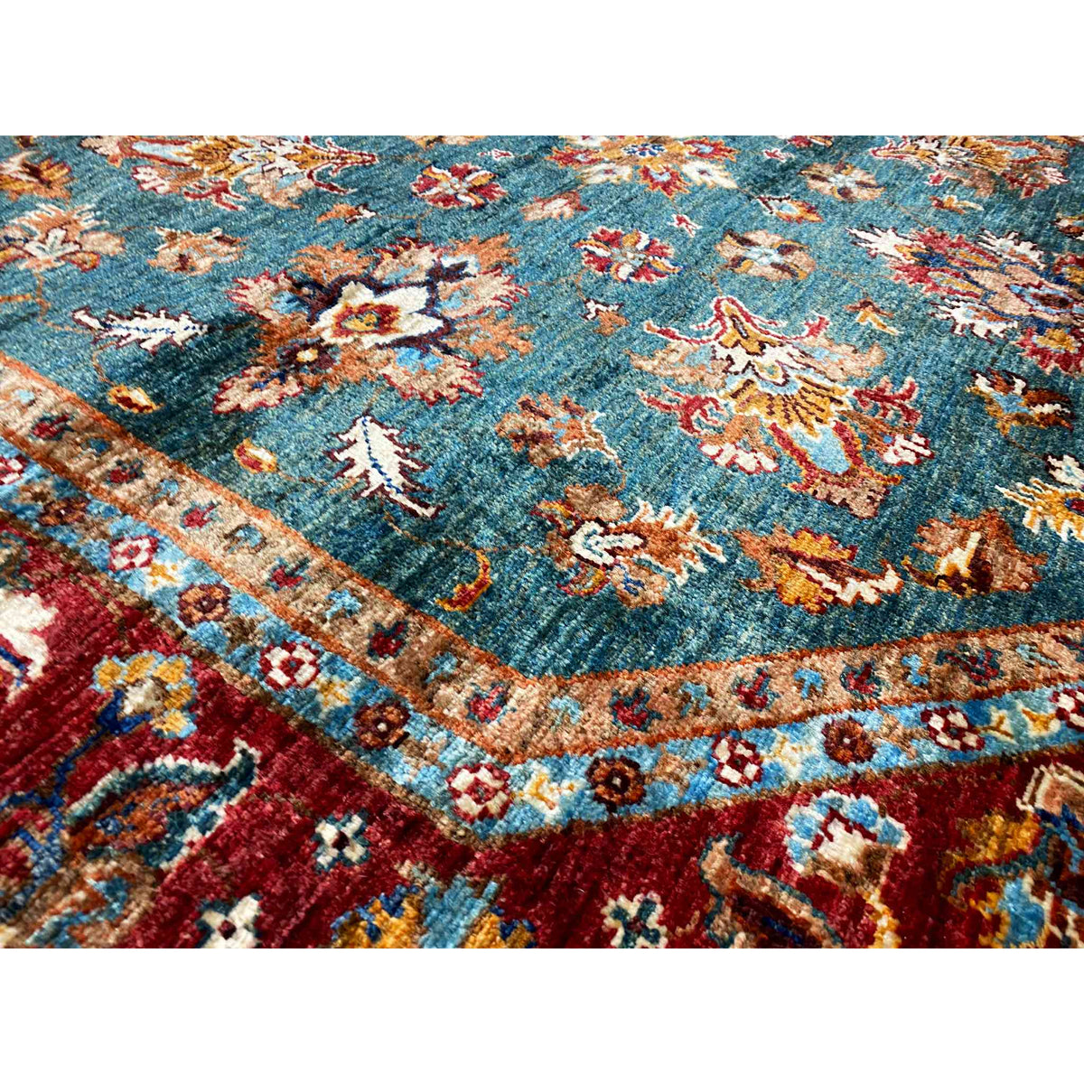 Carpet detail with a delicate floral pattern in teal and red, along with gold accents