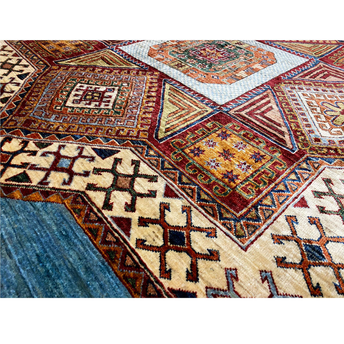 Close-up of Kazak rug: cross and diamond patterns in blue, beige, and red