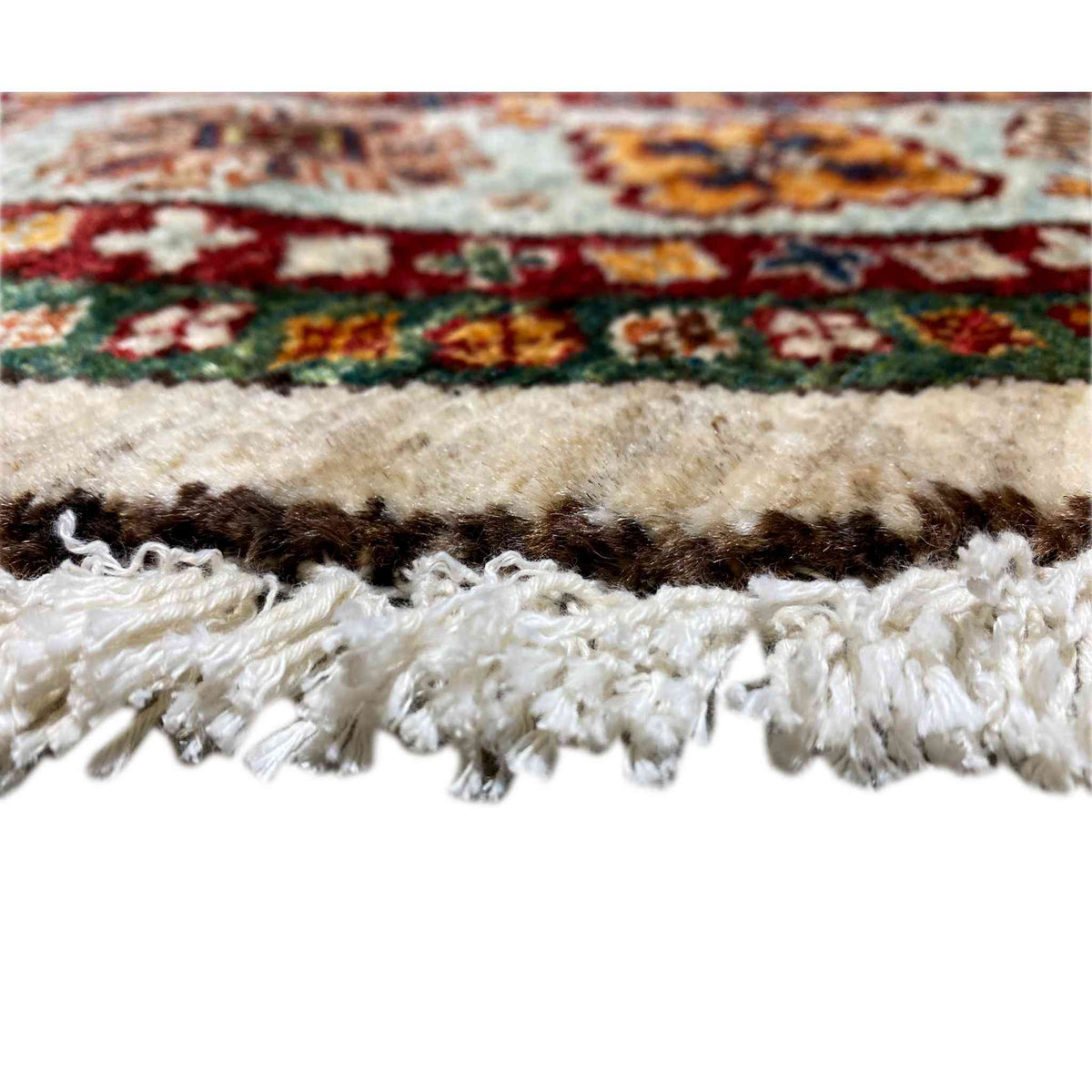 Close-up of a carpet edge with fringe and a multicolored pattern along the border, woven surface