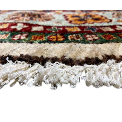 Close-up of a carpet edge with fringe and a multicolored pattern along the border, woven surface