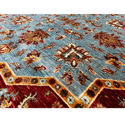 Close-up of a carpet pattern: light blue background with rust-colored and gold ornaments
