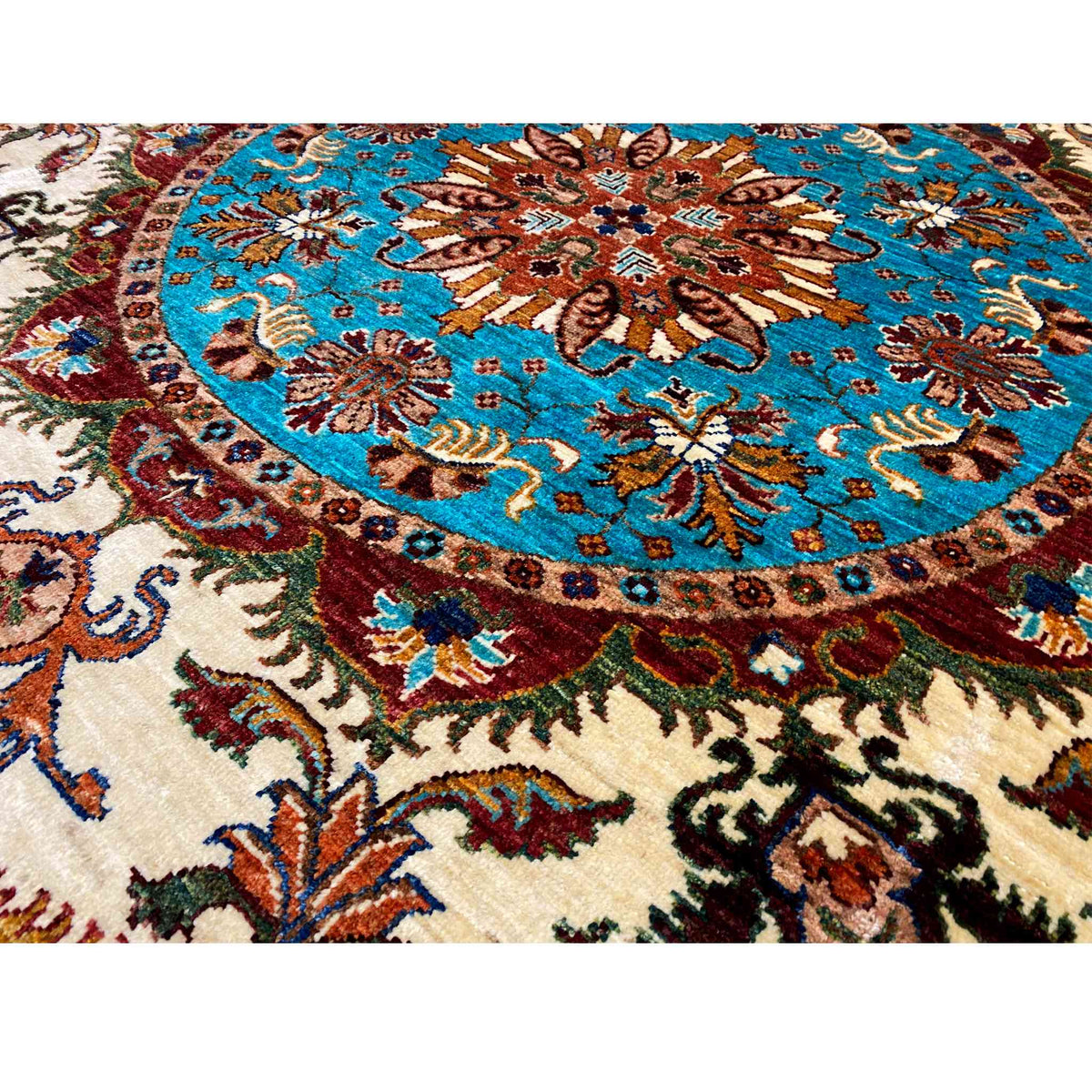 Detail crop: turquoise medallion with a brown ornamental element, surrounded by floral patterns.