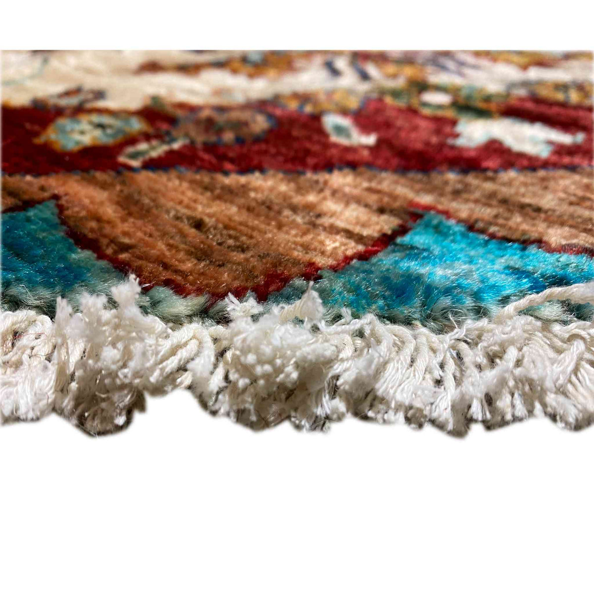 Carpet edge with white pile fringe and a turquoise-brown pattern along the hem