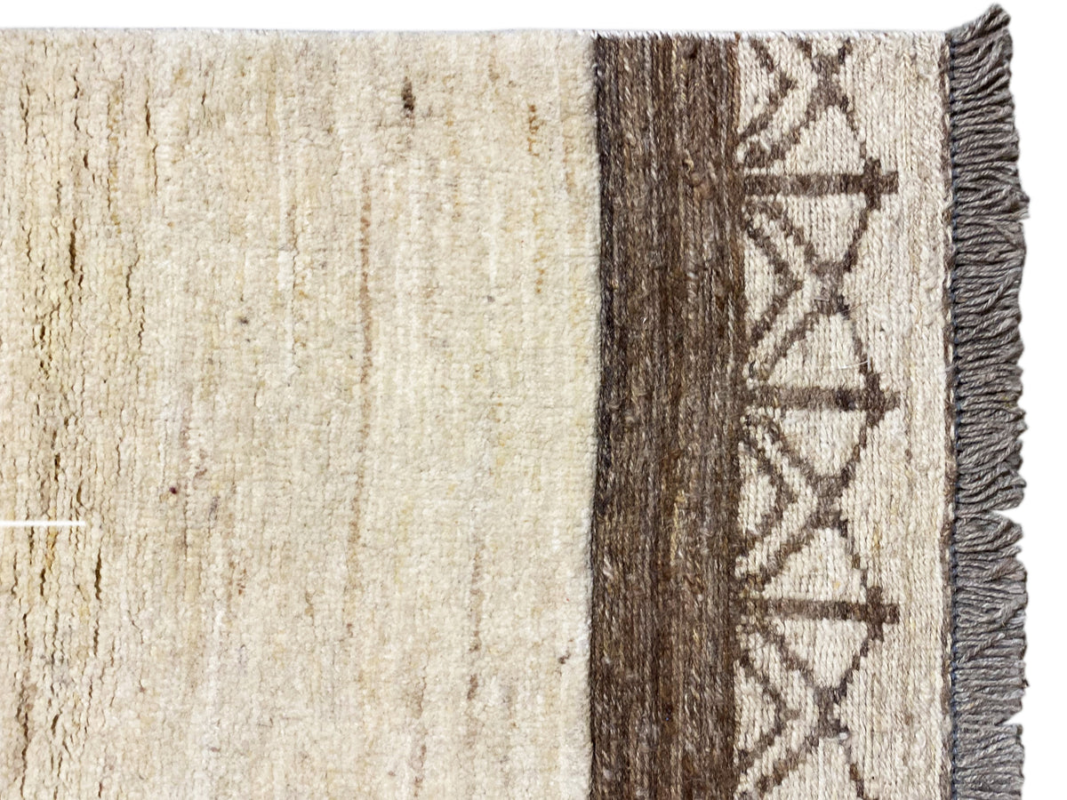 Kelim Gabbeh Teppich Detail: beiger Flor, dunkle Seitenkante und grafisches Randmuster