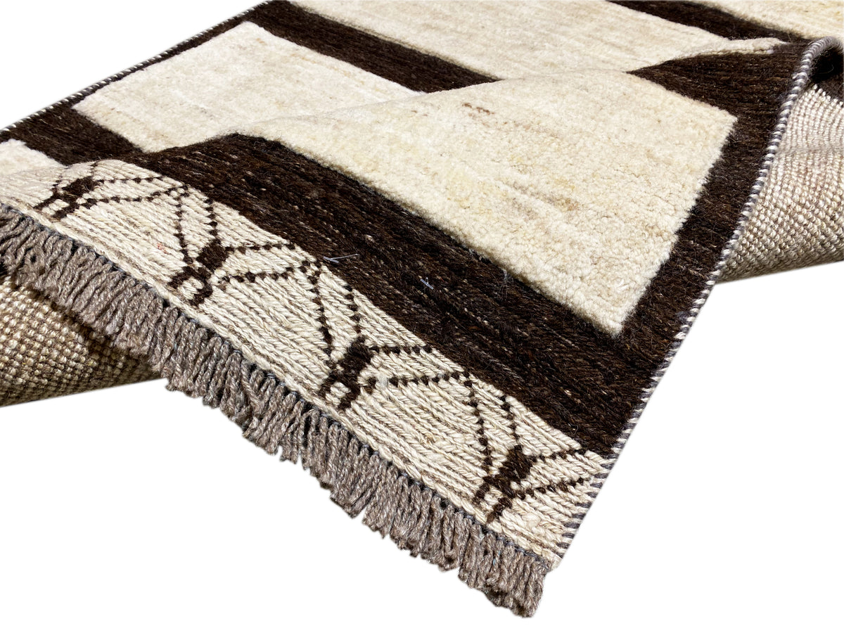 Eckansicht Kelim Gabbeh Teppich mit Zierbordüre, Fransen und Streifen in Creme und Dunkelbraun