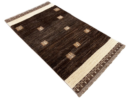 Kelim-Teppich von schräg oben: dunkles Braun, beige Zierborte und Fransen am Rand