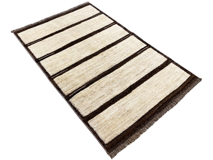 Rectangular beige kilim rug with dark stripes, photographed diagonally, with fringes.