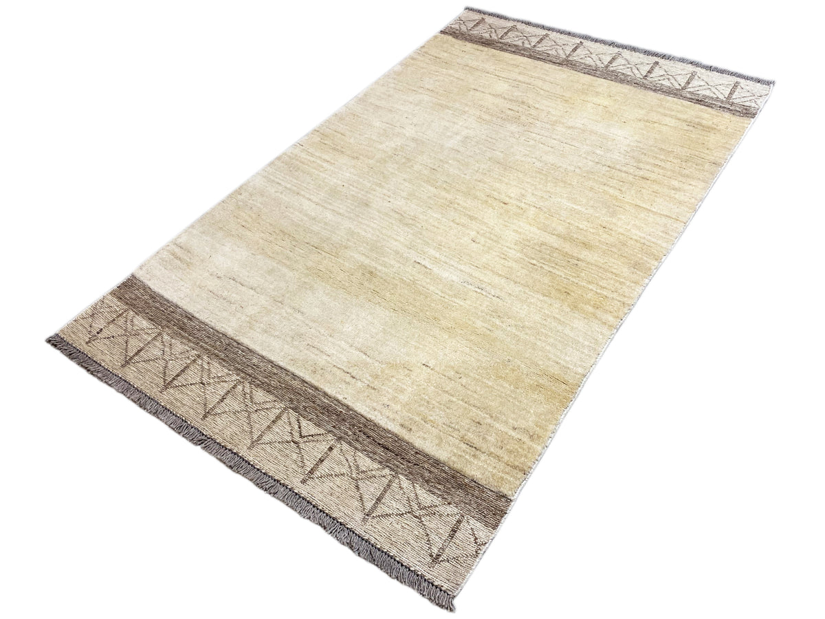 Gabbeh kilim rug in a diagonal view, cream-colored pile with dark brown striped borders