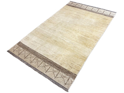 Gabbeh kilim rug in a diagonal view, cream-colored pile with dark brown striped borders