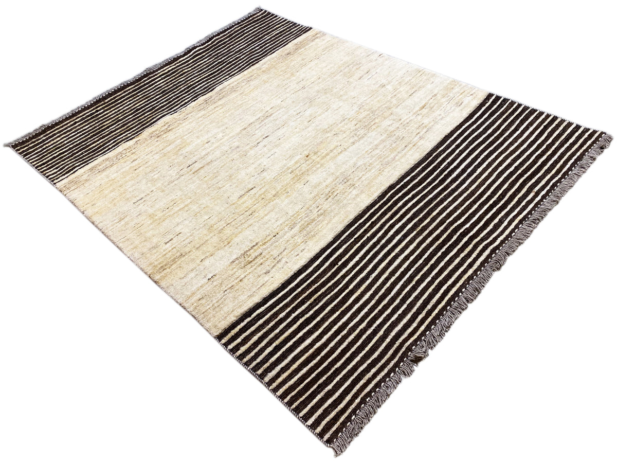 Kelim-Teppich in Rautenansicht: beige Fläche, schwarze Streifen, Fransen am Rand
