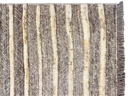 Nahaufnahme vom Kelim-Teppich: senkrechte Streifen in Beige, Grau und Gelb, fransiger Rand