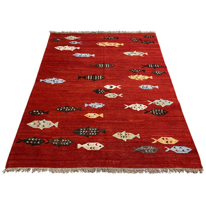 Red kilim rug with a triangular design, multicolored figures, and fringes