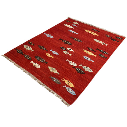 Red kilim rug with colorful figures and fringes along the edges, angled