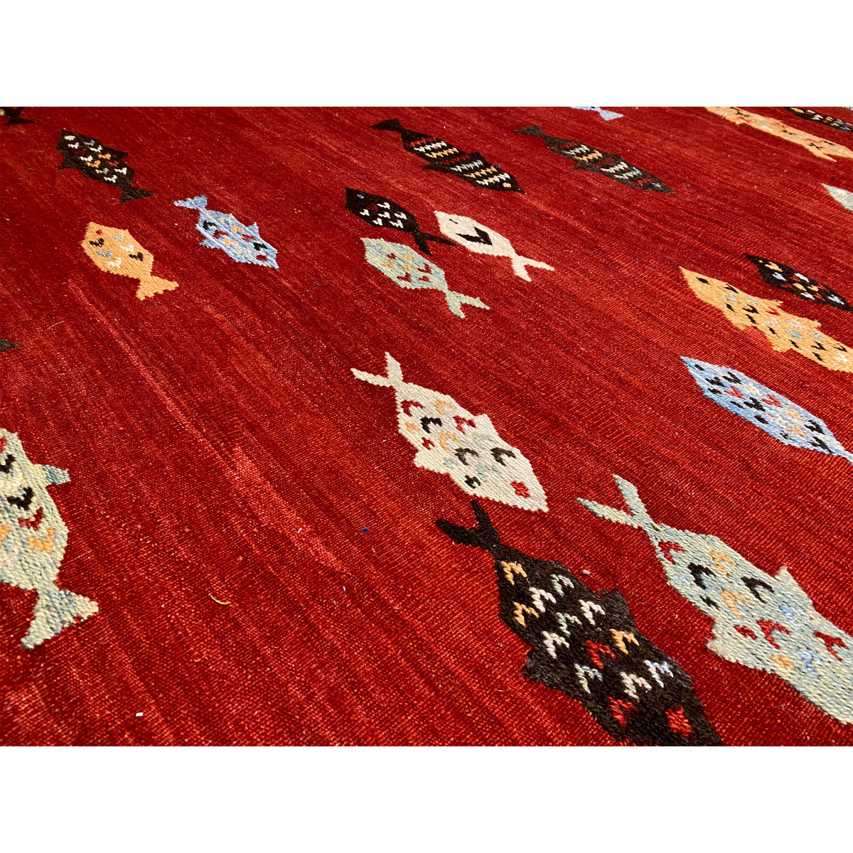 Close-up: red kilim rug with multicolored animal motifs and geometric patterns