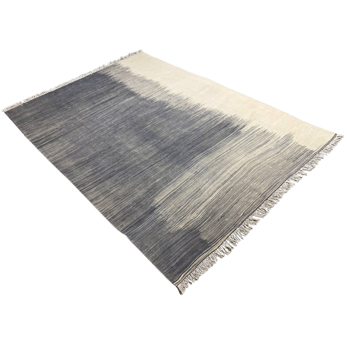 Kilim rug laid diagonally, dark gray with beige accents and fringes