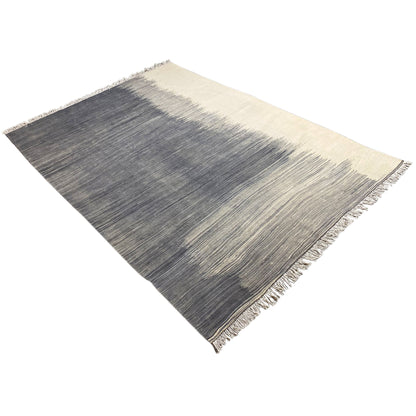 Kilim rug laid diagonally, dark gray with beige accents and fringes