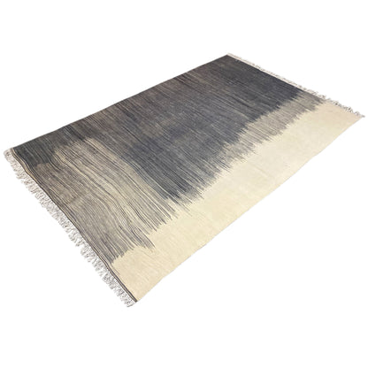 Corner-view kilim rug with a dark center, beige stripes, and fringes