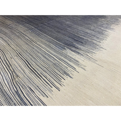 Close-up of a kilim rug: tightly woven lines, dark gray and cream, with fringes