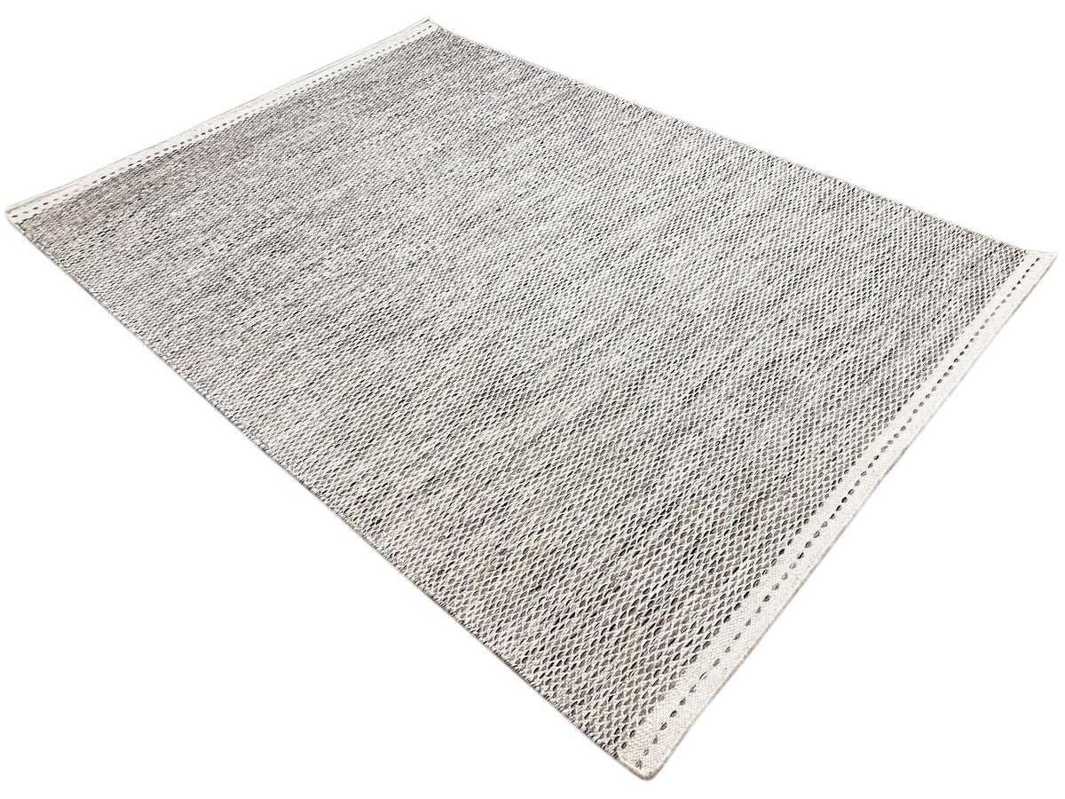 Light gray kilim rug with a dot pattern, diagonally oriented view with a bound edge