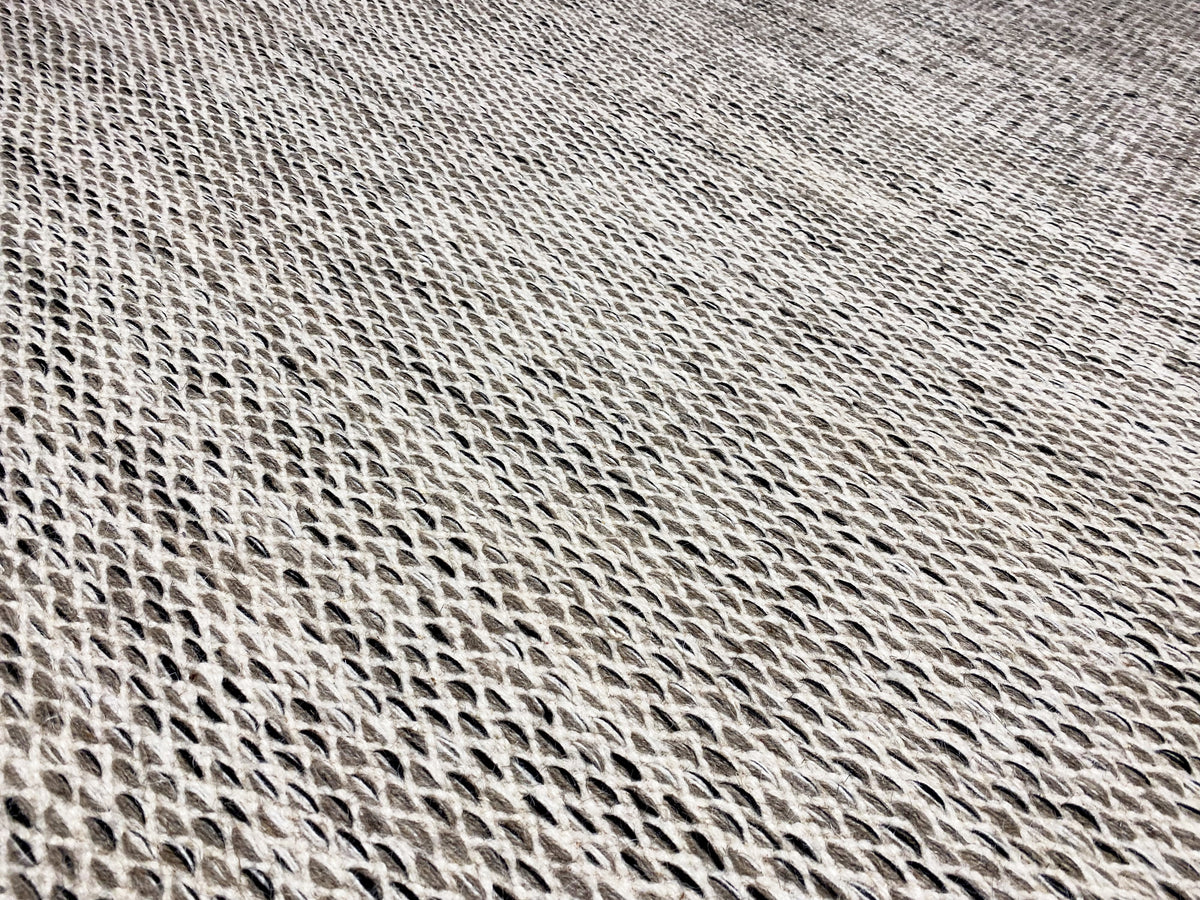 Detailed view of the kilim dot pattern: light gray, tightly woven surface with dark accents