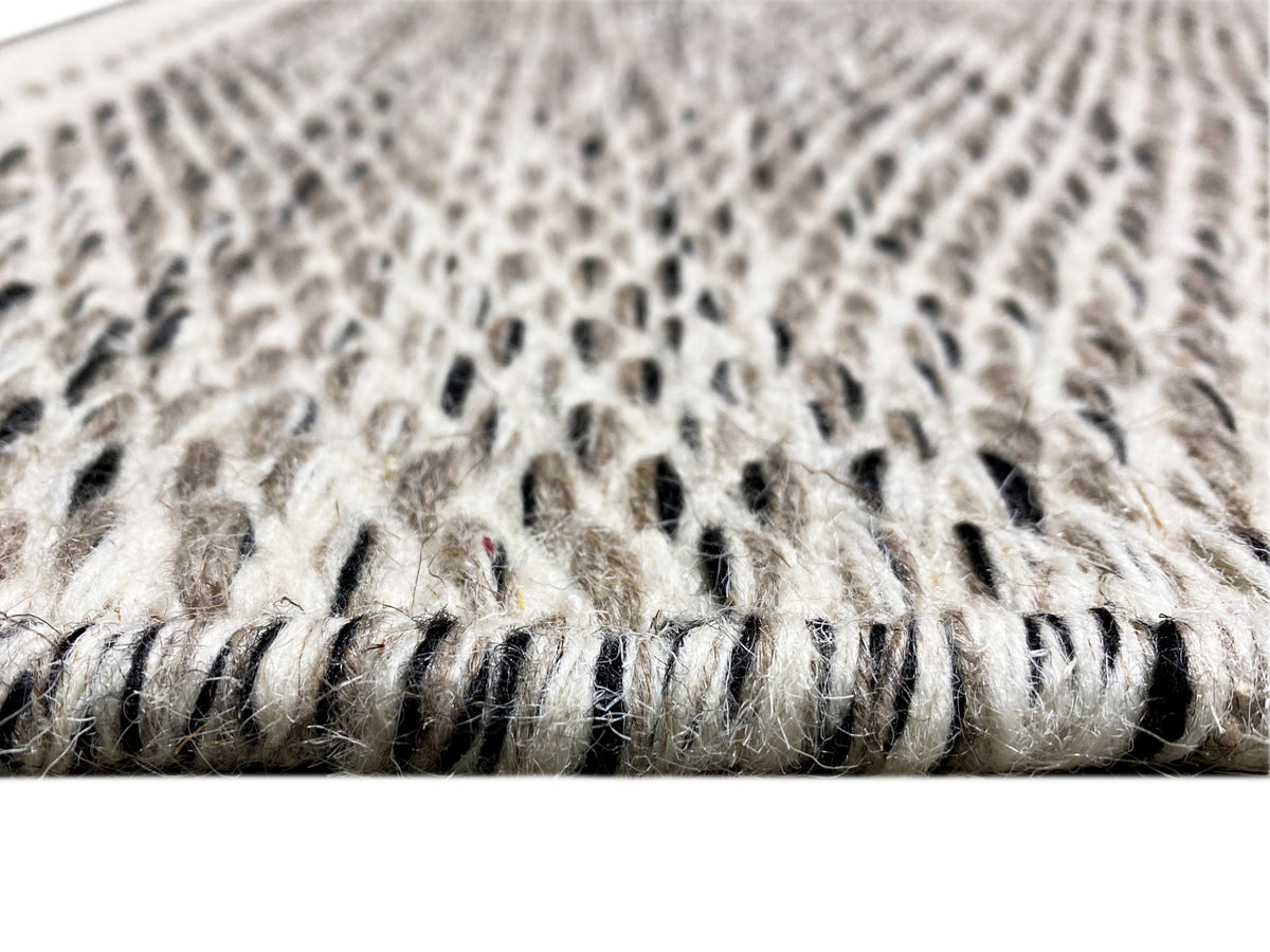 Close-up: kilim rug with a dotted pattern and short fringe along the bottom edge