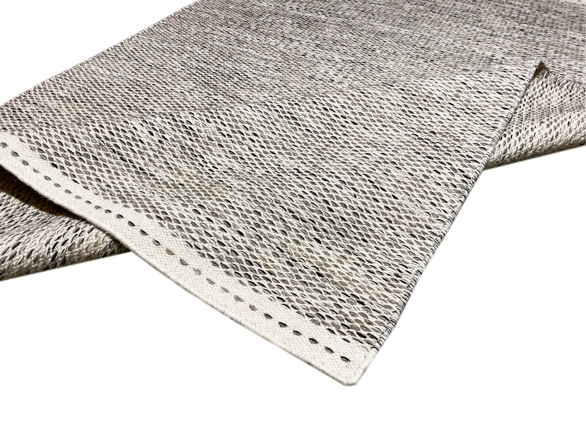 Kilim rug corner with polka-dot pattern, bound edge and short fringes, two-layer view