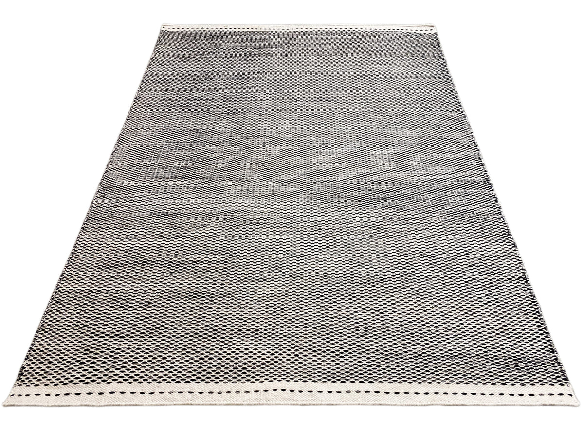 Kilim rug in a dark tone with a subtle pattern and decorative stitching around the edge