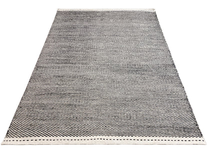 Kilim rug in a dark tone with a subtle pattern and decorative stitching around the edge
