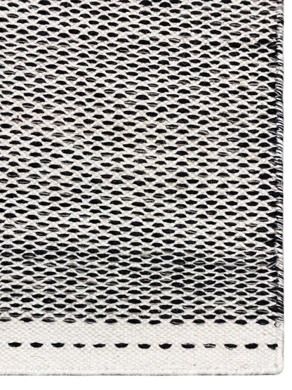 Kilim rug detail: fine hole-and-ring weave in dark gray with light edges