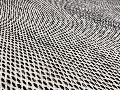 Kilim rug detail: dense dark gray grid weave, with a light-colored edge finish