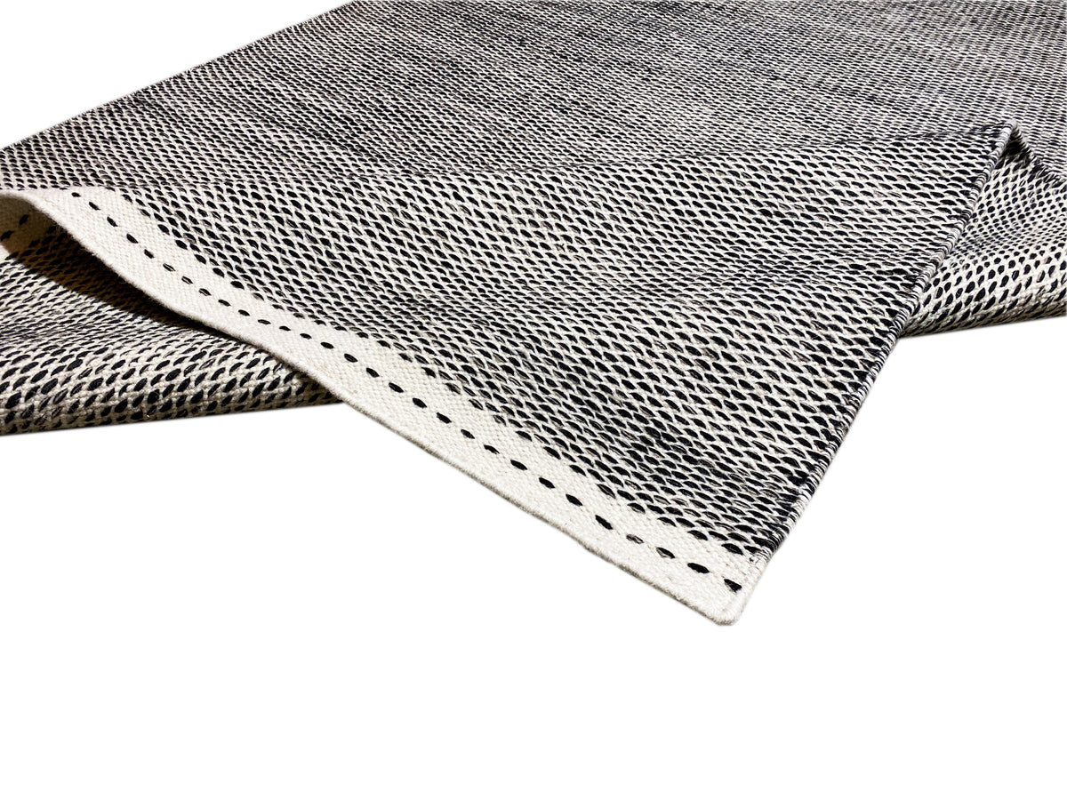 Kilim rug corner with light decorative stitching and visible weave texture