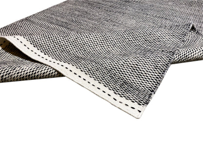Kilim rug corner with light decorative stitching and visible weave texture