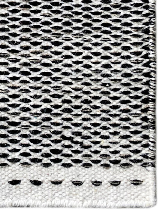 Kelim-Teppich Detailansicht: schwarz-weißes Lochmuster, gepunktete Ziernaht unten