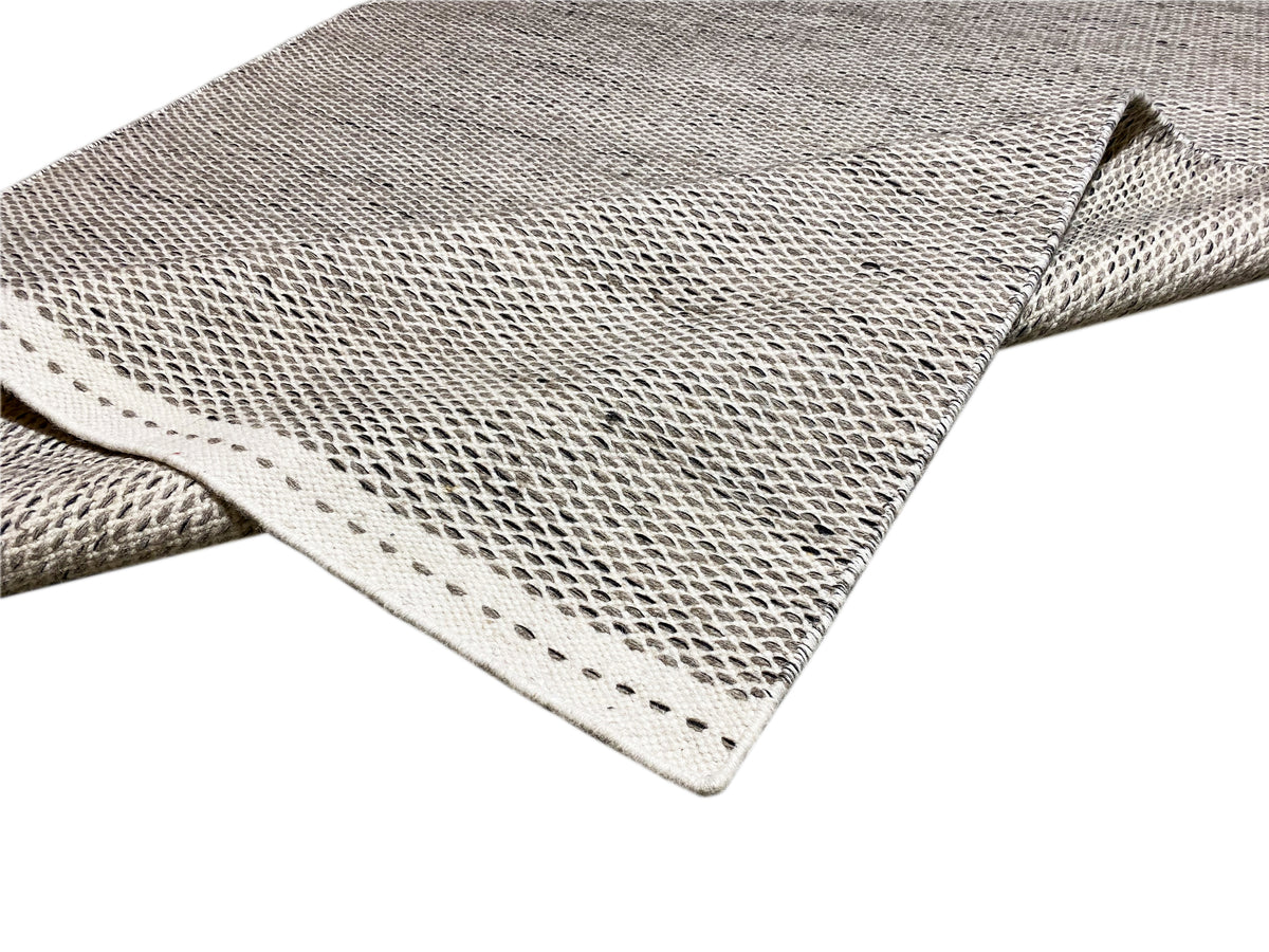 Kilim rug in silver, corner detail, woven pattern and bound edges