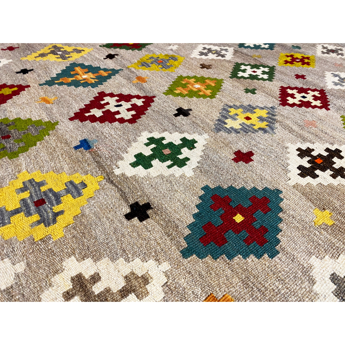 Close-up: Kilim with colorful diamonds and cross motifs on a beige/gray background