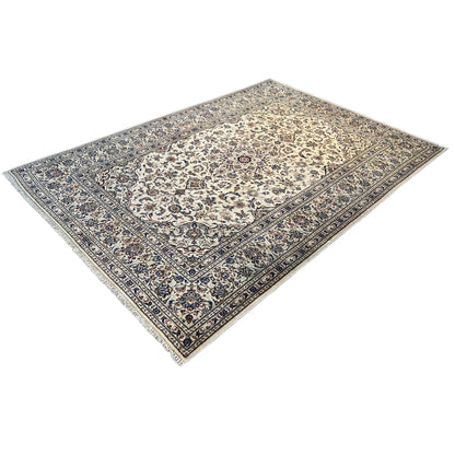 Keshan rug with a beige background and blue border ornament in three-quarter view