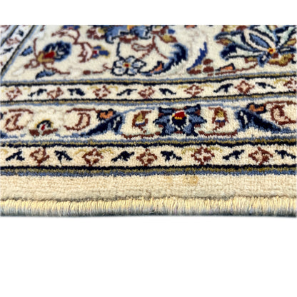 Close-up of a Keshan rug: lower border with a blue pattern and fringes