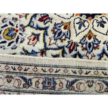 Close-up of Keshan carpet: pile with blue-red ornaments and woven finishing edge