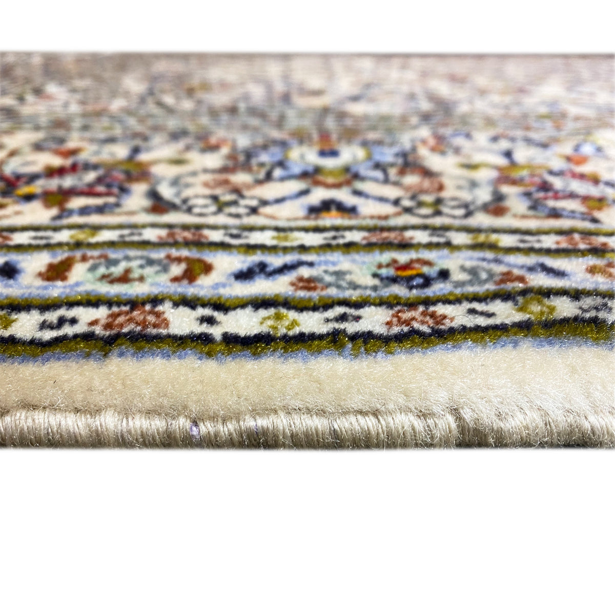 Detail at the edge of the rug: cream-colored pile with a multicolored border and fringes