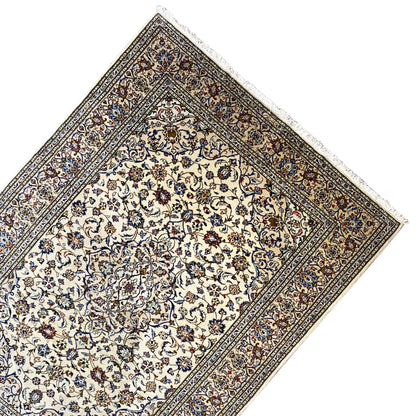 Keshan rug in an angled view with a cream-colored medallion field and ornamental border