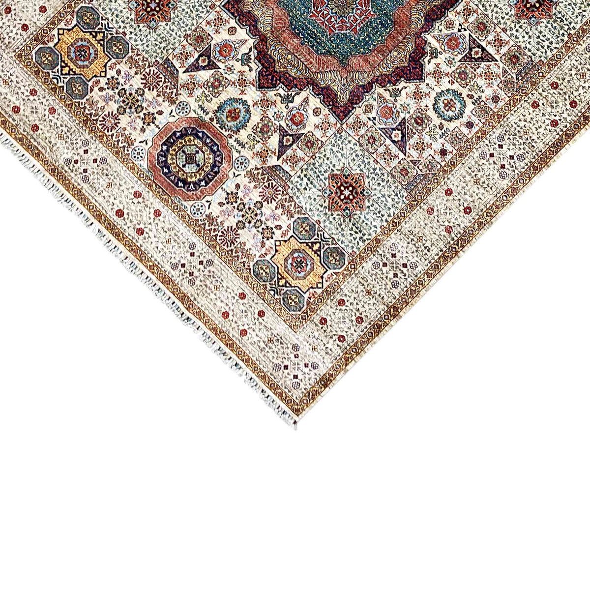 Corner of the beige wool rug with an ornamental border and fine fringes along the edge