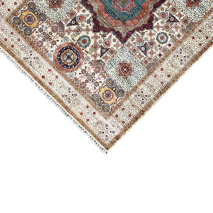 Corner of the beige wool rug with an ornamental border and fine fringes along the edge