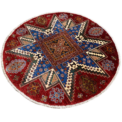 Round wool rug with a red background and blue zigzag and cross pattern, white border