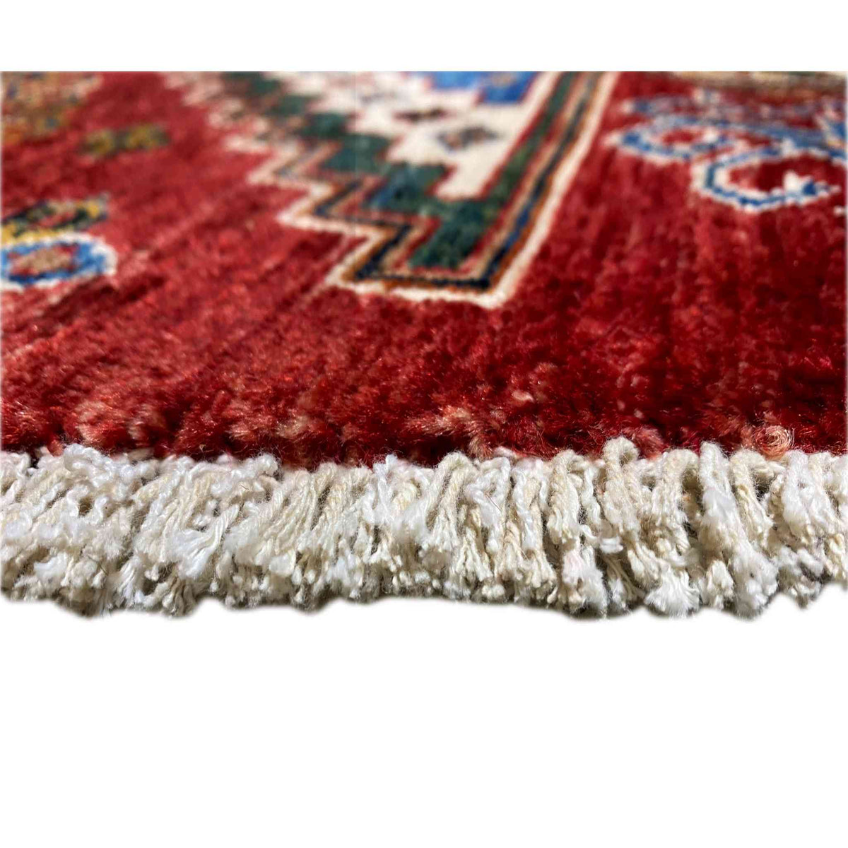 Close-up: soft wool rug with a white fringed edge along the bottom finish